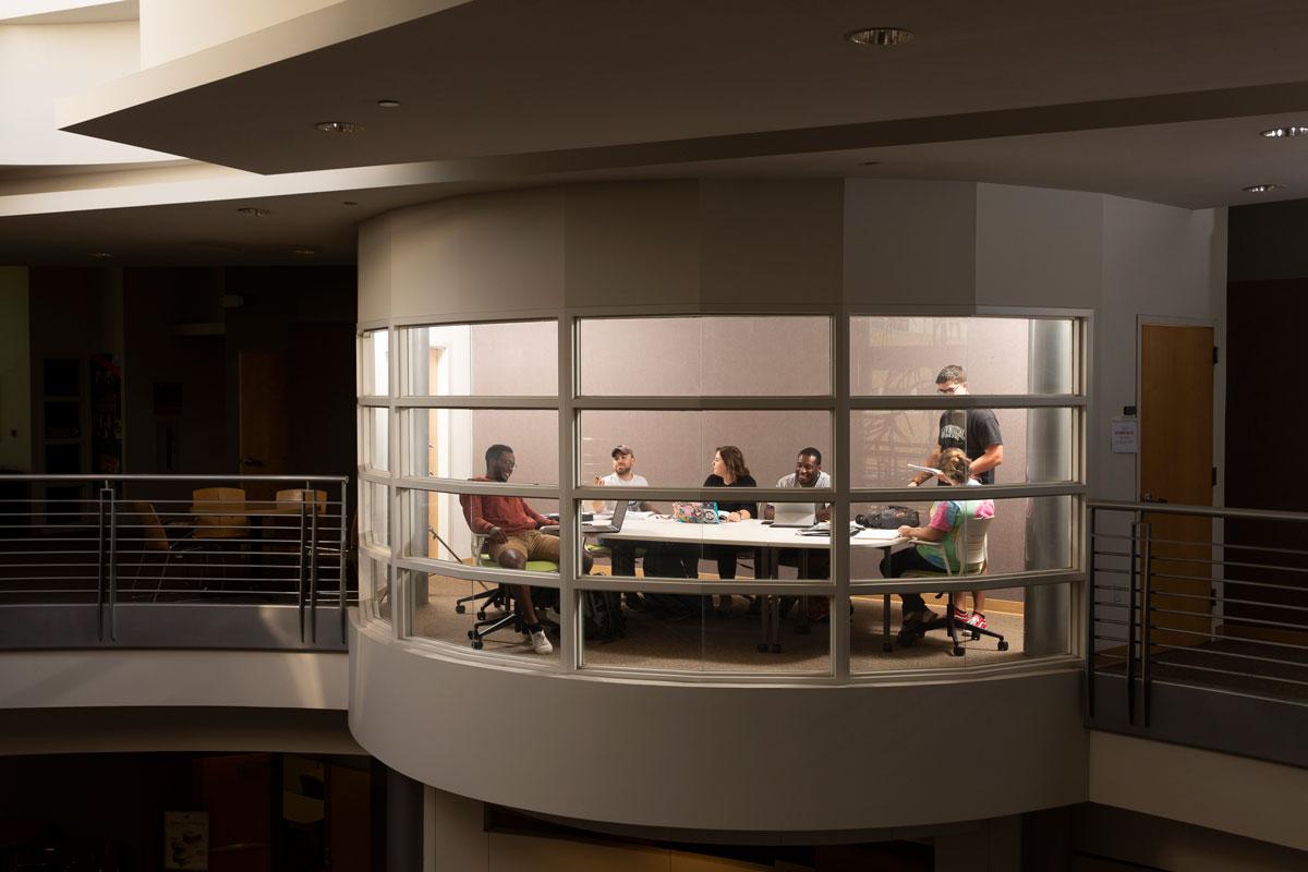 Students collaborate in a conference room overlooking the Davis College of Business & Technology lobby.