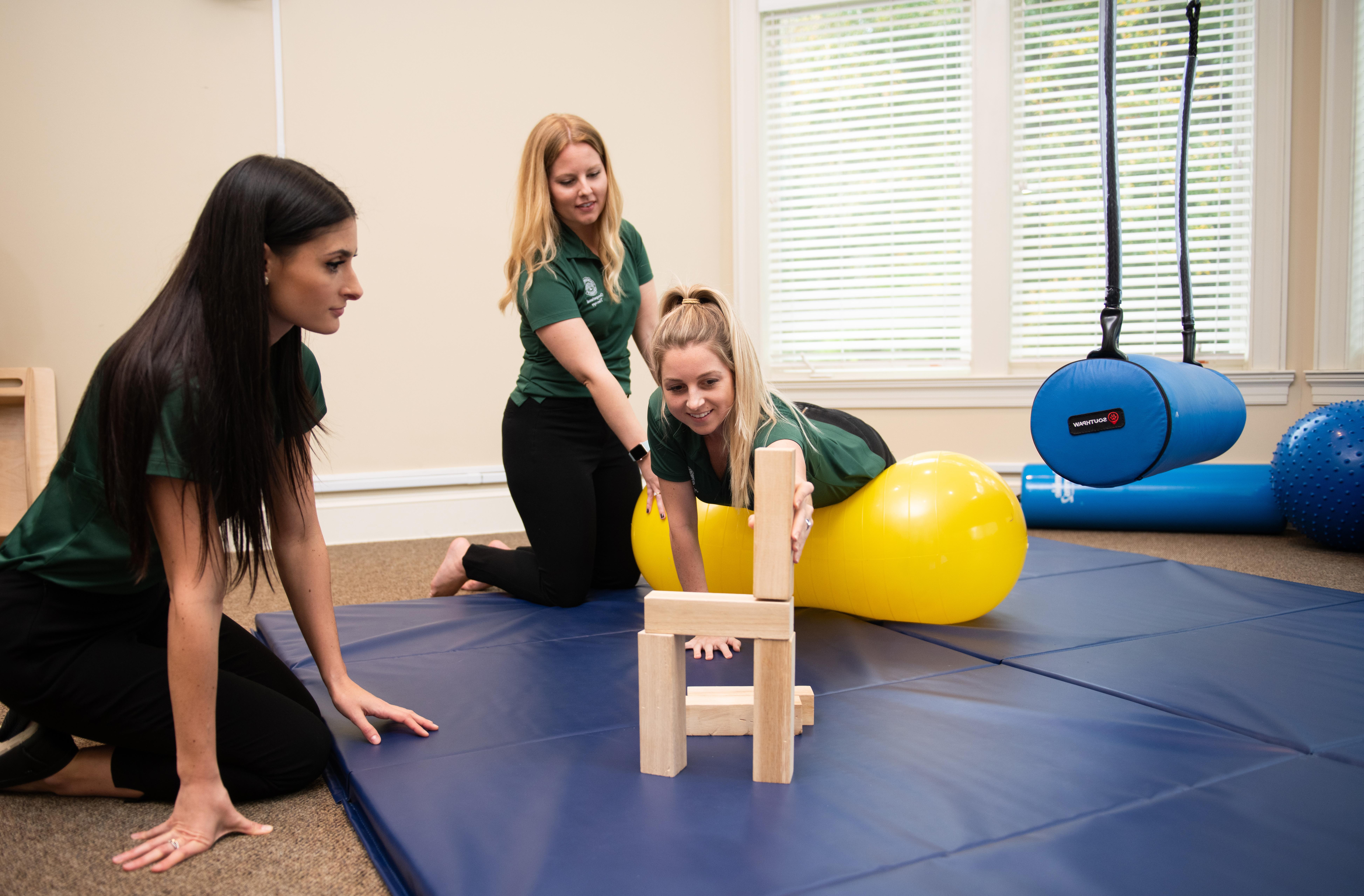 Three Occupational Therapy students demonstrating tools used during sessions